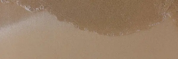 Plaża z mokrym piaskiem i wodą zbliżenie — Zdjęcie stockowe