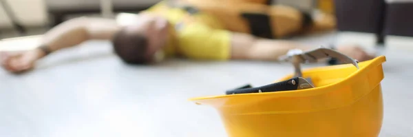 Sárga biztonsági sisak fekszik a padlón közel halott munkás koncepció — Stock Fotó