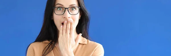 Mujer sorprendida con gafas cubre su boca con su mano —  Fotos de Stock