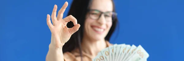 Жінка тримає доларові купюри в руках і показує чіткий жест крупним планом — стокове фото