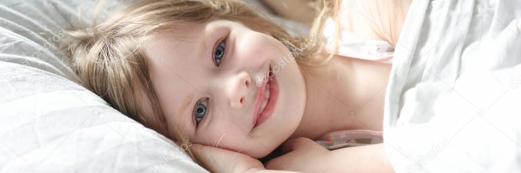 Little beautiful girl lying in bed with mom