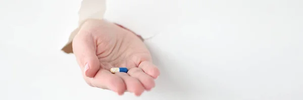 Mão retirando a cápsula do medicamento do papel rasgado — Fotografia de Stock