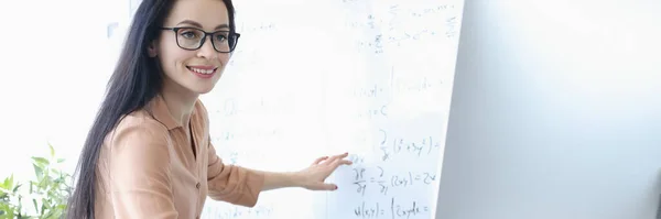 Woman teacher showing math formulas in computer screen