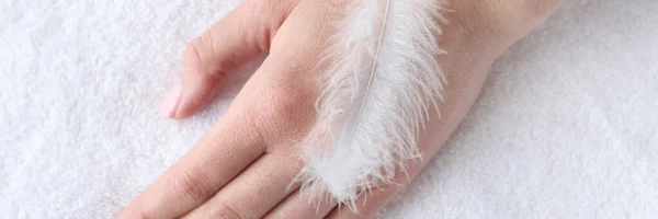 Soft white feather lying on woman hand closeup — Stock Photo, Image
