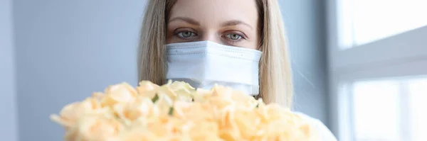 Donna in maschera medica protettiva che tiene mazzo di fiori — Foto Stock
