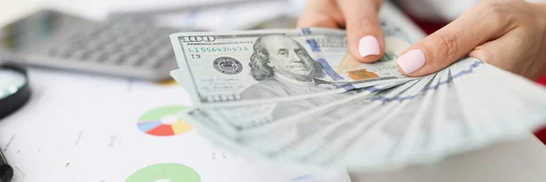 Nelle mani femminili banconote da cento dollari sul tavolo sono figure commerciali e finanziarie nei grafici — Foto Stock