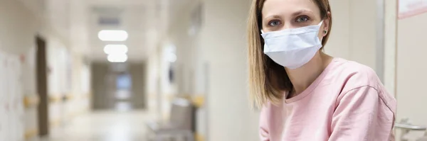 Retrato de mulher em máscara médica protetora senta-se no corredor hospitalar — Fotografia de Stock