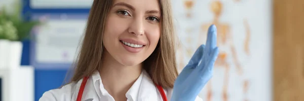 Sorrindo médico feminino colocando luvas médicas — Fotografia de Stock