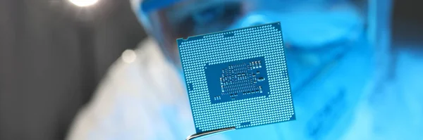 Man i skyddsdräkt och glasögon håller datorn mikrochip med pincett närbild — Stockfoto