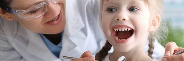 Dentista esaminando bocca di bambina con strumenti — Foto Stock