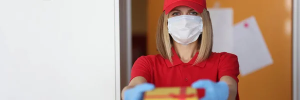 Γυναίκα courier σε προστατευτική ιατρική μάσκα και γάντια δίνοντας δώρο — Φωτογραφία Αρχείου