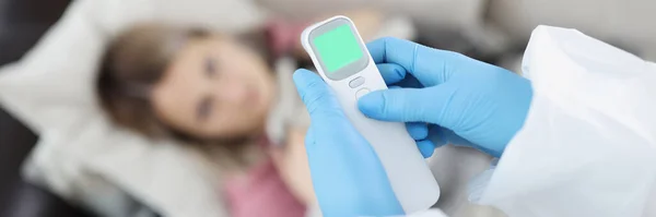 Médico en guantes que mide la temperatura de la mujer con termómetro sin contacto en el primer plano del hogar — Foto de Stock
