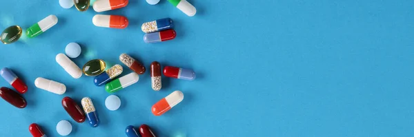 Pílulas médicas multi-coloridas jazem no fundo azul — Fotografia de Stock