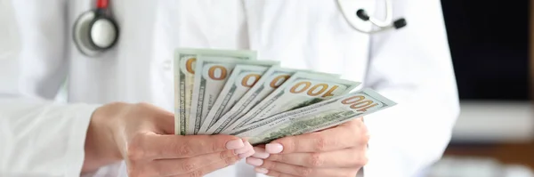 Doutor detém notas de dólar em dinheiro em suas mãos — Fotografia de Stock