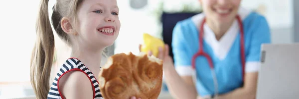 笑顔の女の子食べるパンを背景に医師 — ストック写真