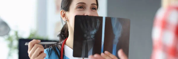 Läkaren undersöker en röntgen av patientens hand — Stockfoto