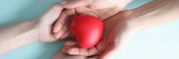 Små röda hjärta ligger i händerna på två personer — Stockfoto