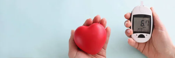 Coração pequeno e glicosímetro com indicadores mantidos na mão — Fotografia de Stock