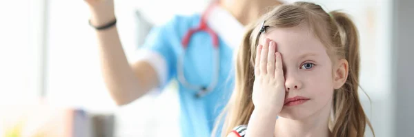 Petite fille couvrant ses yeux avec sa main à rendez-vous ophtalmologiste — Photo