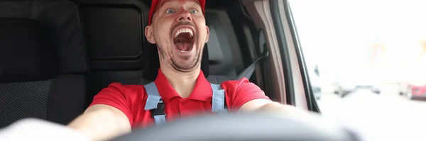 Feliz mensajero masculino cabalgando detrás del volante del coche con la boca abierta — Foto de Stock