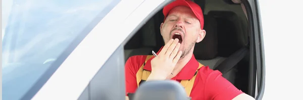 Mensajero masculino sentado detrás del volante del coche y bostezando —  Fotos de Stock