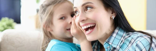 Little girl whispering secret to mom ear at home — Stock Photo, Image