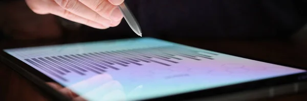 Мужская рука держит стилус над экраном планшета с коммерческими графиками в темноте — стоковое фото