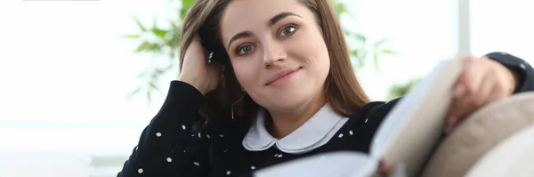 Retrato de uma jovem sorridente sentada no sofá com livro — Fotografia de Stock