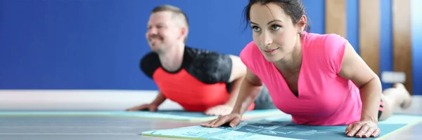 Homem e mulher realizam flexões no ginásio em esteiras — Fotografia de Stock