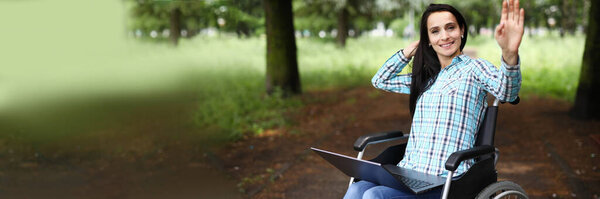 Женщина в инвалидном кресле машет рукой в приветствии