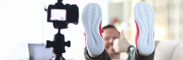 Erkek blog yazarı spor ayakkabısının tabanını kameraya gösteriyor — Stok fotoğraf