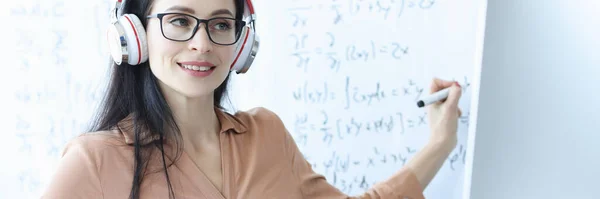 Woman teacher with headphones conducts online math class — Stock Photo, Image