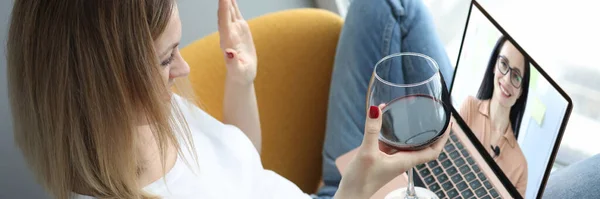 Kvinnan hälsar sin vän med videosamtal och håller ett glas vin i sina händer — Stockfoto