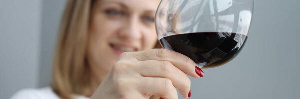 Woman holds glass of red wine in her hand