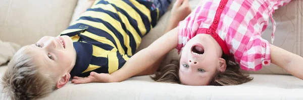 Bambino e ragazza sdraiati sul divano a testa in giù a casa — Foto Stock