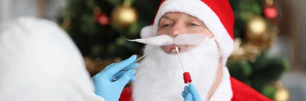 Médico en traje antipeste tomando frotis de PCR por infección por coronavirus de Santa Claus — Foto de Stock