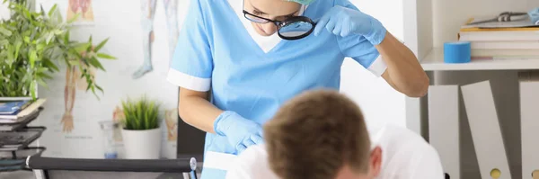 Dermatovenerologist médico examinando a pele em nádegas de paciente masculino usando lupa — Fotografia de Stock