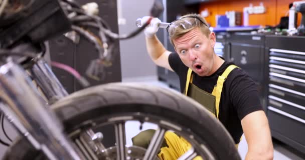 Homem surpreendido reparador reparando motocicleta e coçando a cabeça com chave filme 4k — Vídeo de Stock