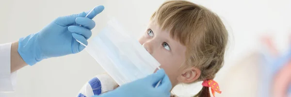 Läkare sätta skyddande medicinsk mask på liten flicka på kliniken — Stockfoto