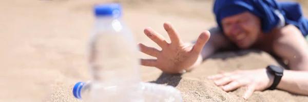 Trockener Mann kriecht auf Sand nach Trinkwasserflasche in Nahaufnahme — Stockfoto