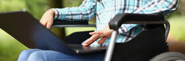 Woman in wheelchair on her knees with laptop