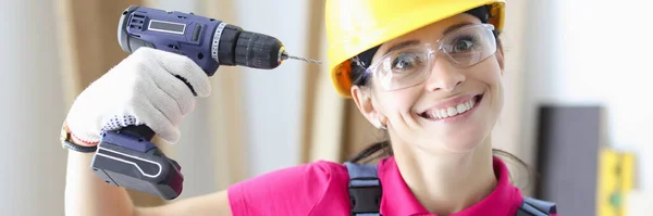 Glimlachende vrouw bouwer houdt boor dicht bij haar hoofd — Stockfoto