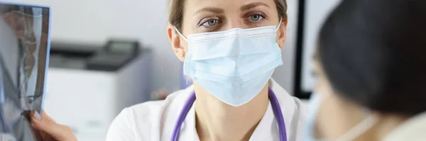 Dokter draagt beschermende medische masker toont patiënt X-ray — Stockfoto