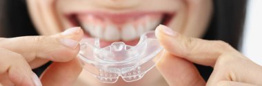 Gülümseyen kadın diş beyazlatmak için plastik ağız koruyucusu tutuyor.