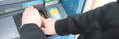 Adamın biri ATM 'den şifre giriyor ve eli kapalı kapatıyor.