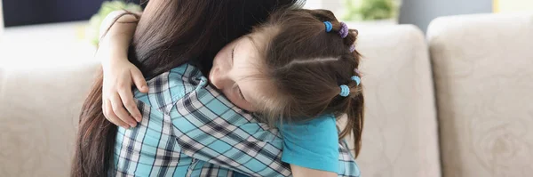 Bambina seduta sulle ginocchia della madre e abbracciandola a casa — Foto Stock