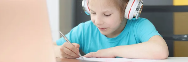 Kleines Mädchen mit Kopfhörern lernt zu Hause vor dem Laptop — Stockfoto