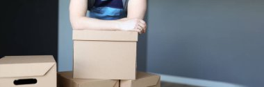 Tulumlu bir adam ellerini karton kutuların üzerine koyuyor.