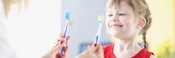 Liten flicka som väljer tandborste hos tandläkaren på kliniken — Stockfoto