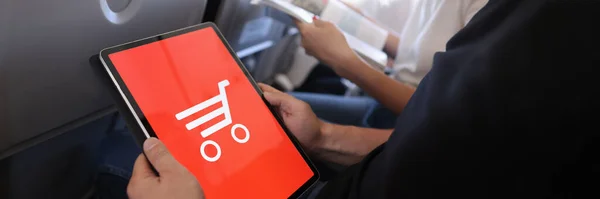 Hombre sostiene tableta hace compras en línea mientras está sentado en cabina de avión — Foto de Stock